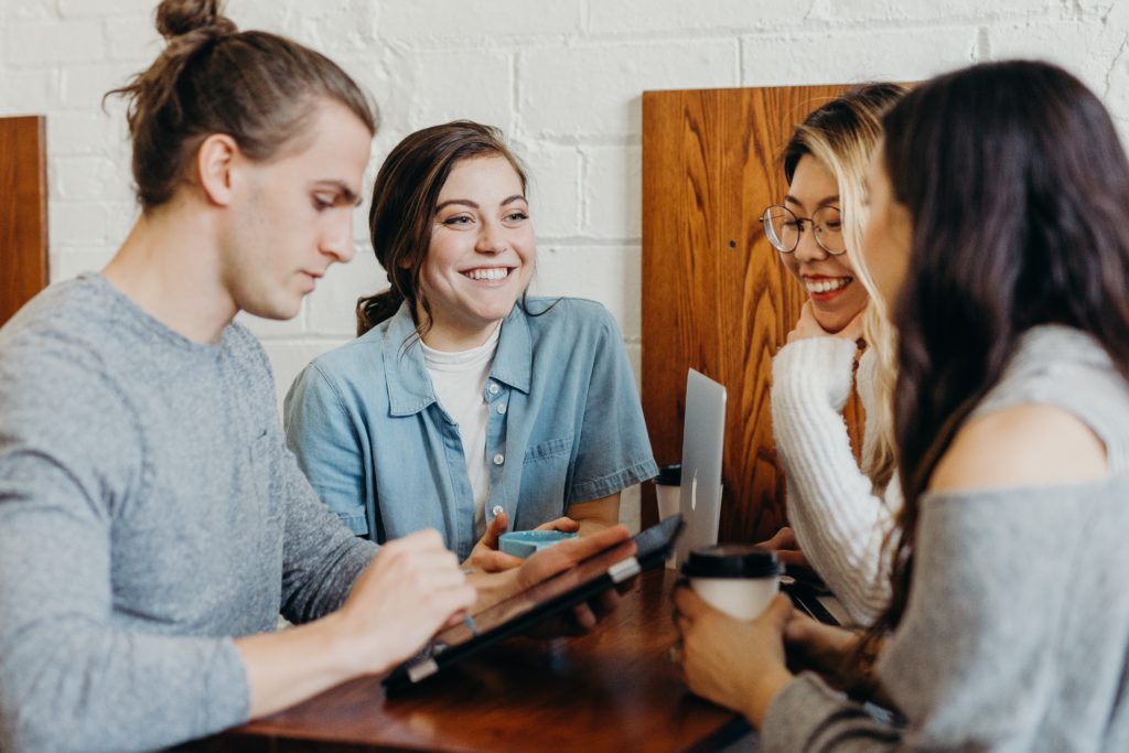 Image of young people talking and laughing at a cafe table